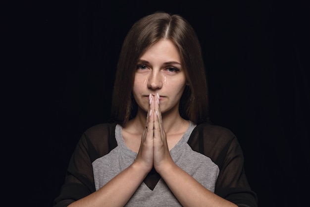 Portret van een jonge vrouw geïsoleerd op zwarte muur close-up