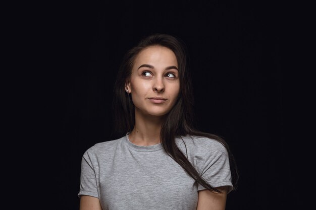 Portret van een jonge vrouw geïsoleerd op zwarte studio achtergrond close-up. Photoshot van echte emoties van vrouwelijk model. Dromend en lachend, hoopvol en gelukkig. Gelaatsuitdrukking, concept van menselijke emoties.