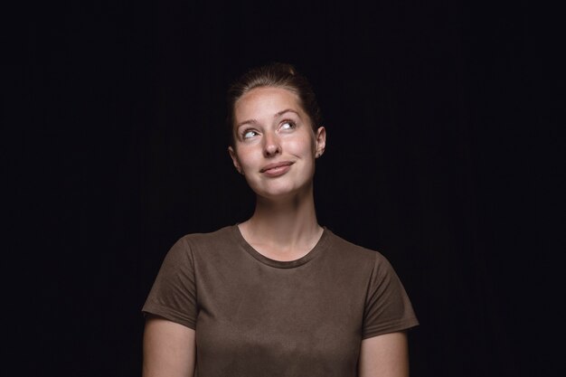 Portret van een jonge vrouw geïsoleerd op zwarte studio achtergrond close-up.