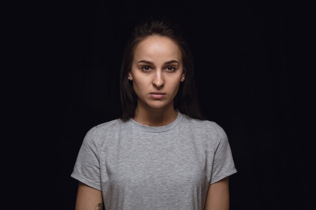 Portret van een jonge vrouw geïsoleerd op zwarte studio muur close-up