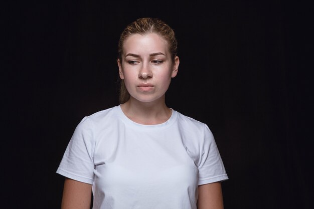 Portret van een jonge vrouw geïsoleerd op zwarte studio muur close-up