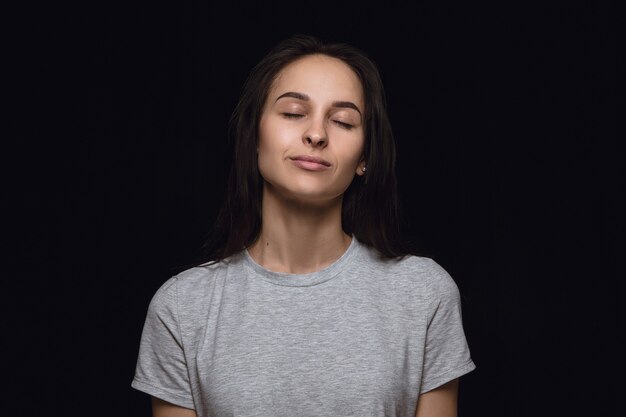 Portret van een jonge vrouw geïsoleerd op zwarte studio muur close-up