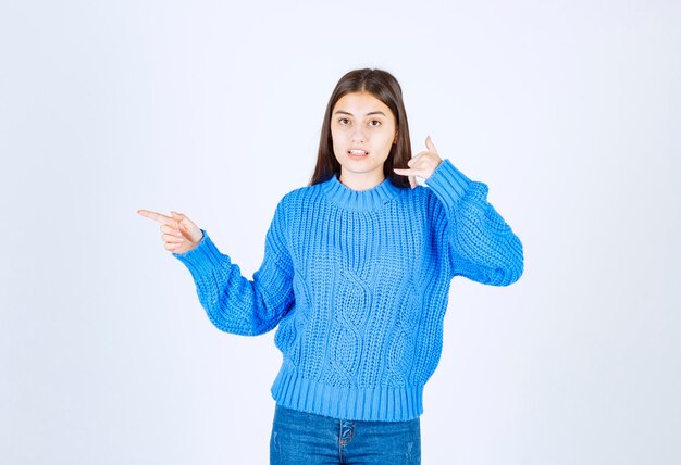 Portret van een jonge vrouw in blauwe trui staande op wit.