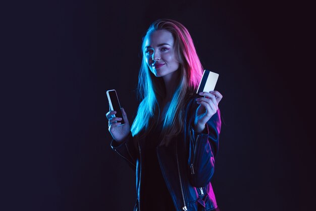 Portret van een jonge vrouw in neonlicht op donkere achtergrondkleur. De menselijke emoties, zwarte vrijdag, cyber maandag, aankopen, verkoop, financieel concept.