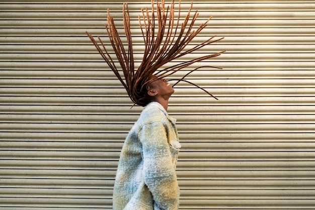 Portret van een jonge vrouw met afro-dreadlocks die pronkt met haar haar terwijl ze in de stad is