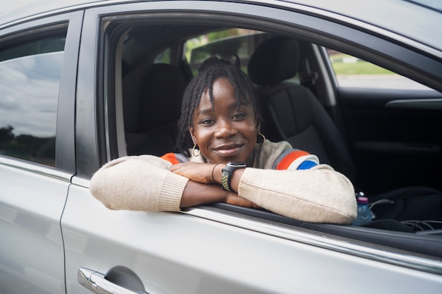 Portret van een jonge vrouw met afro dreadlocks poseren met auto
