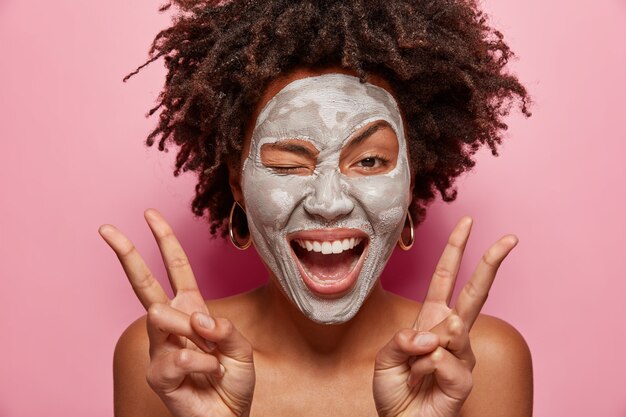 Portret van een jonge vrouw met Afro-kapsel en gezichtsmasker