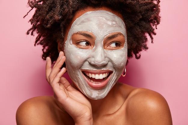 Portret van een jonge vrouw met afro-kapsel en gezichtsmasker