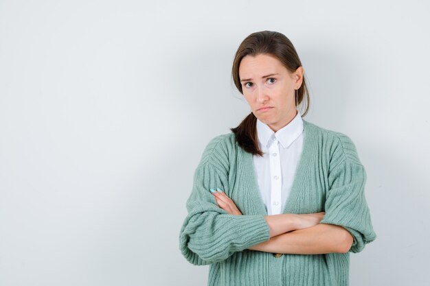 Portret van een jonge vrouw met armen gevouwen in blouse, vest en teleurgesteld vooraanzicht