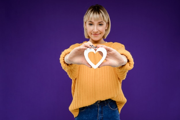 Gratis foto portret van een jonge vrouw met decor hart over paarse muur