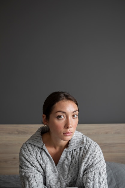 Portret van een jonge vrouw met een laag zelfbeeld die thuis in bed zit