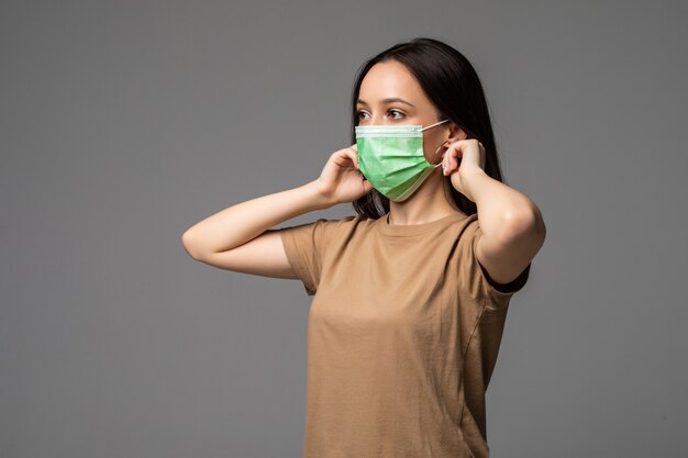 Portret van een jonge vrouw met een medisch masker geïsoleerd op grijs