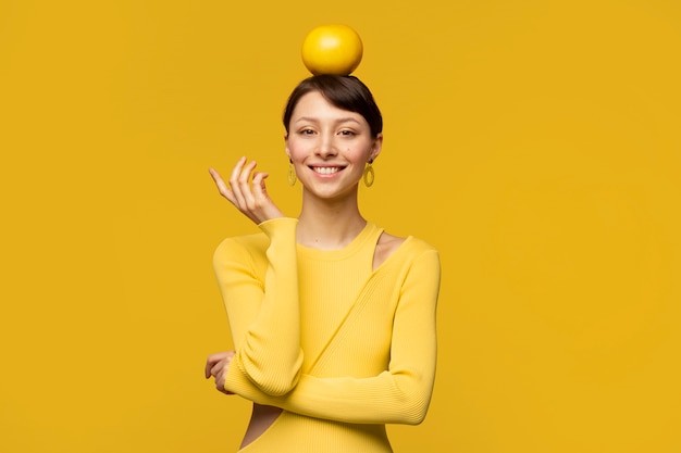 Portret van een jonge vrouw met grapefruit op haar hoofd