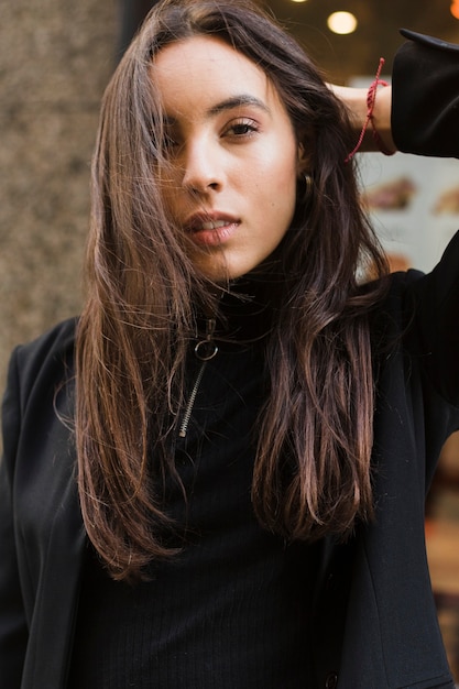 Portret van een jonge vrouw met haar hand achter het hoofd camera kijken