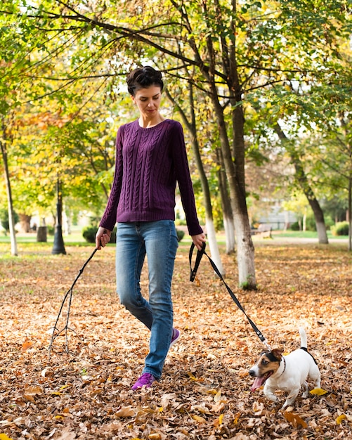Gratis foto portret van een jonge vrouw met haar hond in het park