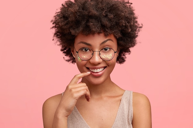 Portret van een jonge vrouw met krullend haar en glitter op gezicht