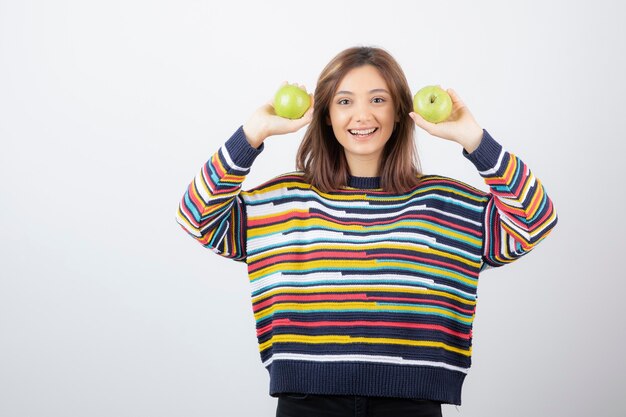 Gratis foto portret van een jonge vrouw met twee verse groene appels.