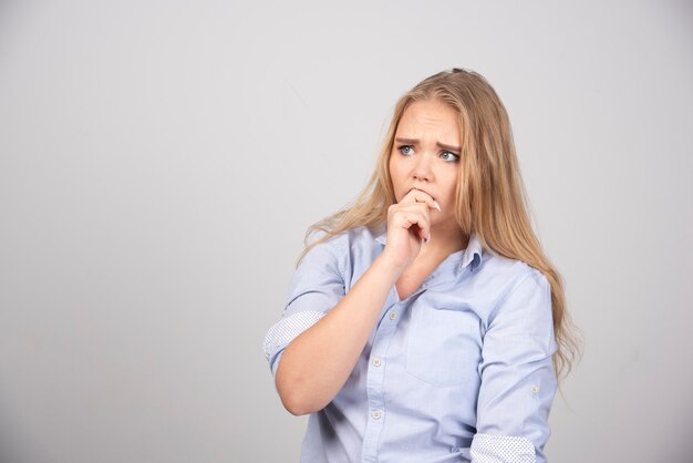 Portret van een jonge vrouw model permanent en poseren tegen grijze muur.