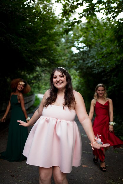Gratis foto portret van een jonge vrouw naast haar vrienden op prom
