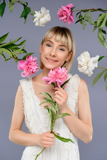 Portret van een jonge vrouw onder bloemen over grijze muur