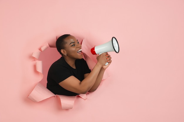 Gratis foto portret van een jonge vrouw op roze gescheurde doorbraakachtergrond