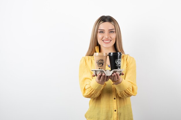 Portret van een jonge vrouw poseren met kopjes koffie op witte achtergrond.