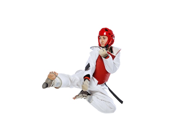 Portret van een jonge vrouw, taekwondo-atleet in beweging, training geïsoleerd op witte achtergrond