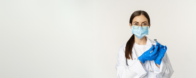 Portret van een jonge vrouwelijke arts met een medisch gezichtsmasker en uniform met vaccin covid vaccinatie ca