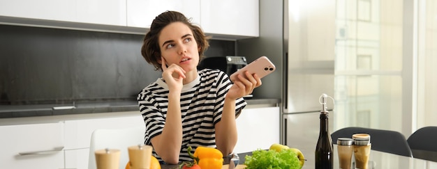 Gratis foto portret van een jonge vrouwelijke foodblogger die op sociale media een veganistisch salade recept plaatst in de