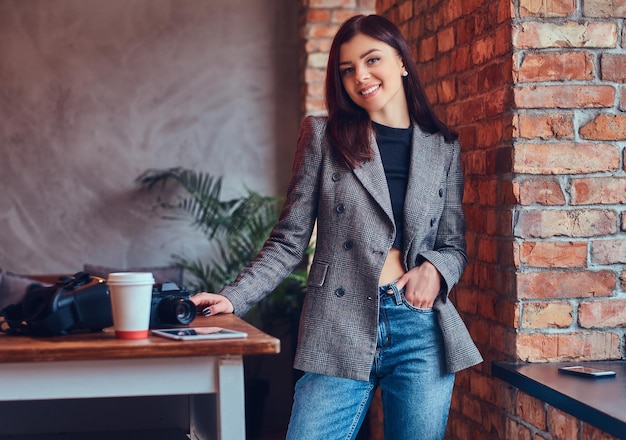 Portret van een jonge vrouwelijke fotograaf die tegen een baksteen staat