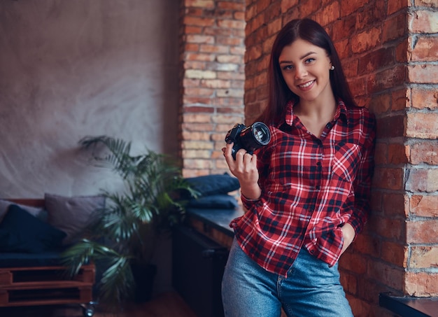 Portret van een jonge vrouwelijke fotograaf in een flanellen hemd en j