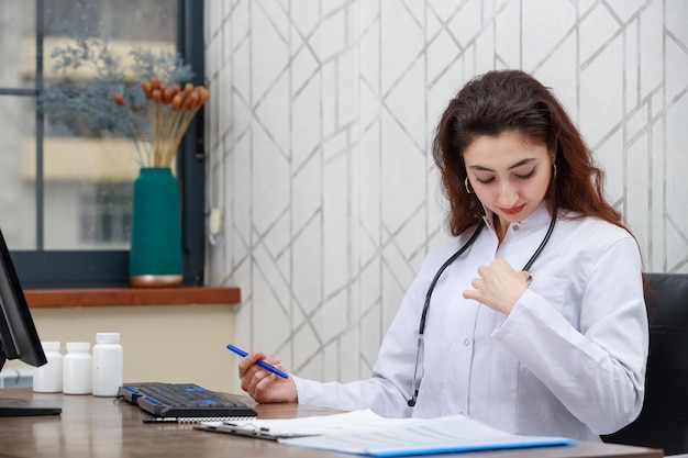 Portret van een jonge vrouwelijke gezondheidswerker die op kantoor zit