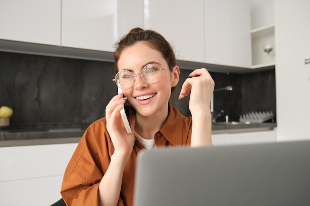 Portret van een jonge vrouwelijke ondernemer die vanuit huis werkt en een telefoongesprek maakt