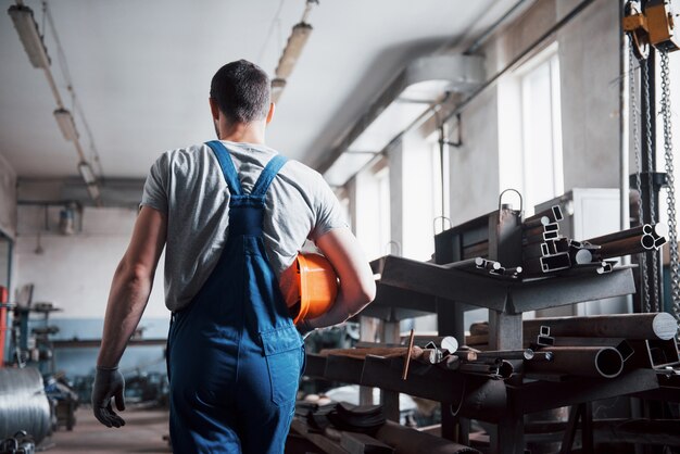 Portret van een jonge werknemer in een bouwvakker bij een grote afvalrecyclingfabriek.