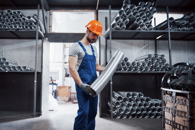 Portret van een jonge werknemer in een harde hoed bij een grote metaalbewerkingsfabriek.