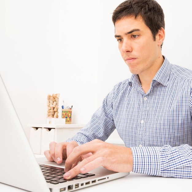 Portret van een jonge zakenman met behulp van laptop op witte tafel