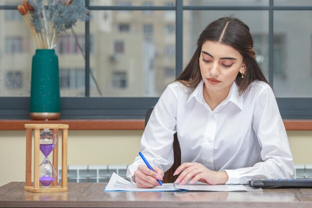 Portret van een jonge zakenvrouw die aan het bureau zit en notities schrijft