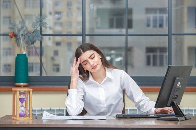 Portret van een jonge zakenvrouw die aan het bureau zit en zich moe voelt Foto van hoge kwaliteit