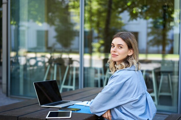 Portret van een jonge zakenvrouw die met een laptop werkt terwijl ze buiten zit, een zakelijke vrouw op video