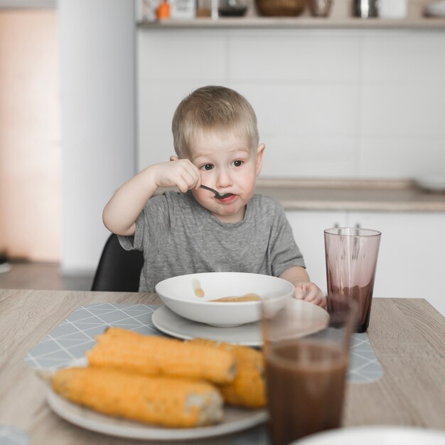 Portret van een jongen die voedsel thuis eet