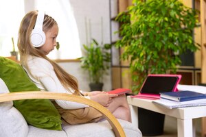 Portret van een klein meisje dat thuis studeert en op een laptop kijkt die met de leraar werkt online onderwijs