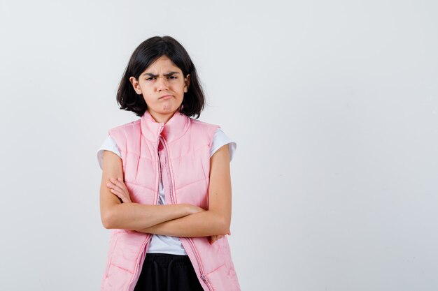 Portret van een klein meisje in wit t-shirt en kogelvrij vest met gekruiste armen