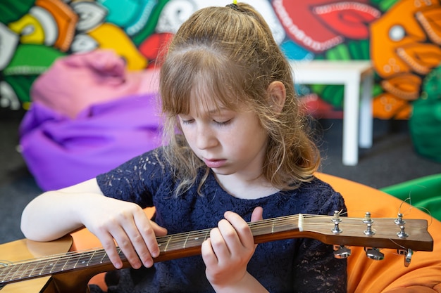 Gratis foto portret van een klein meisje met een akoestische gitaar in haar handen