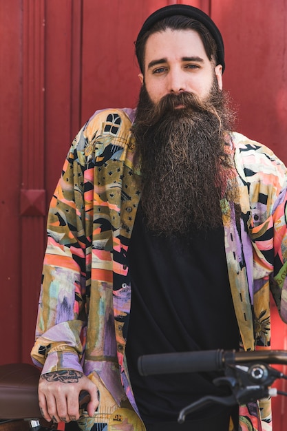 Gratis foto portret van een knappe jongeman met lange baard met zijn fiets