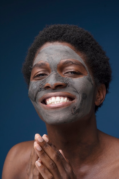 Gratis foto portret van een knappe man die lacht met een houtskoolmasker op zijn gezicht