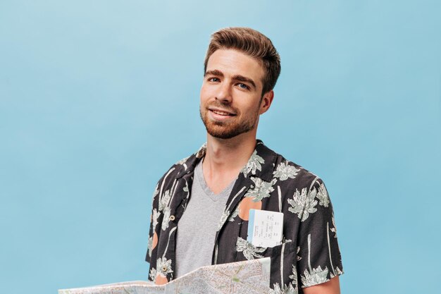 Gratis foto portret van een knappe man met blauwe ogen met een gemberbaard in een grijs t-shirt en een geverfd hemd met kaartjes in zak