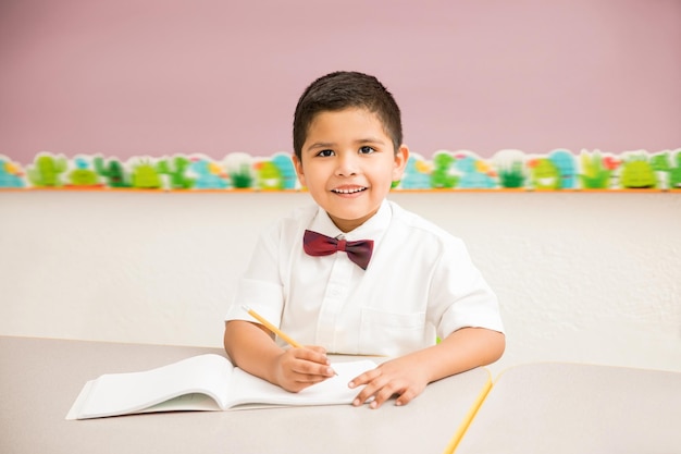 Portret van een knappe Spaanse jongen die een uniform draagt en geniet van lessen op de kleuterschool