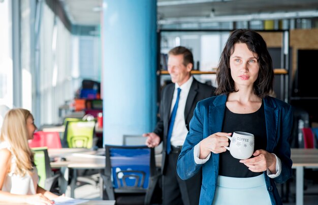 Portret van een kop van de zakenmanholding van koffie in het bureau