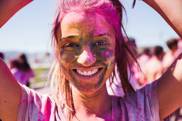 Portret van een lachende jonge vrouw gezicht bedekt met holi kleur