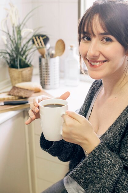 Portret van een lachende jonge vrouw met een kopje koffie